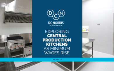 exploring central production kitchens & equipment as minimum wages rise title against a blue background and the picture of a commercial kitchen behind it